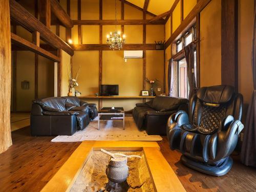 a living room with leather furniture and a chandelier at あさぎり山荘ひばり in Asagiri