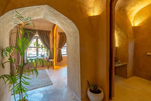 Sunanda by 1810AD - A Boutique Organic Retreat في بوشكار: غرفة بها قوس ونبات بداخلها