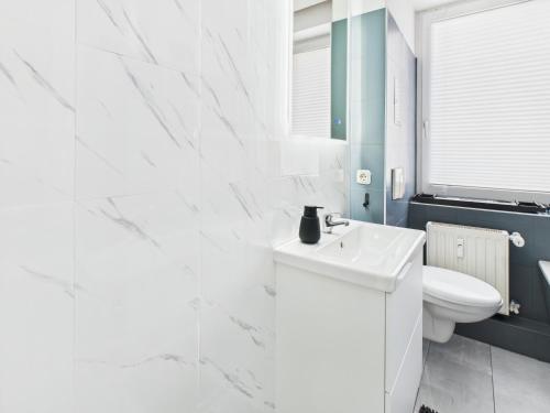 a white bathroom with a toilet and a sink at Loft & Living am Geiseltalsee in Braunsbedra