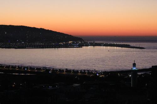 a large body of water with a lighthouse at sunset at 3 Appartements Vue sur Mer dans une maison indépendante in Tangier