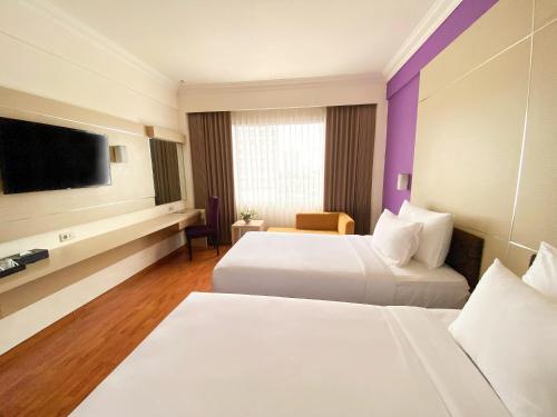 a hotel room with two beds and a flat screen tv at Grand Inna Tunjungan Hotel Surabaya in Surabaya