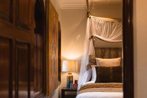 a bedroom with a bed with a canopy and a lamp at Hemingways Eden Residence in Nairobi