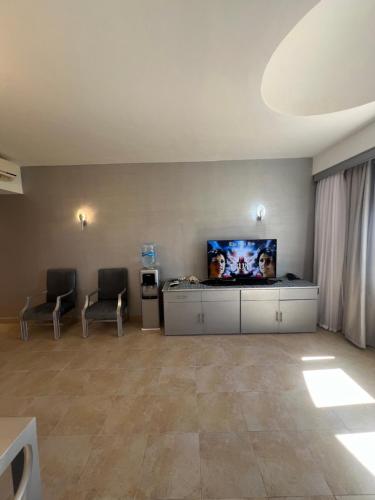 Cette chambre comprend deux chaises et une télévision à écran plat. dans l'établissement classy new 2 bedrooms 2 bathrooms apartment at Domina coral bay sea view with everything you need, à Charm el-Cheikh