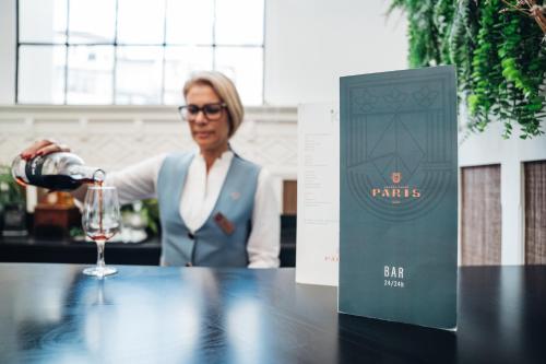 a woman pouring a glass of wine on a table at GRANDE HOTEL PARIS by STAY HOTELS in Porto