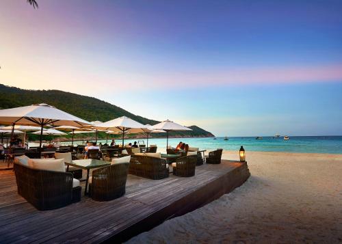 a restaurant on the beach with tables and umbrellas at The Taaras Beach & Spa Resort in Redang Island