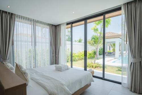 a bedroom with a bed and a large window at Mouana Breeze Mai Khao 5-bedroom Pool Villa 9914 in Mai Khao Beach