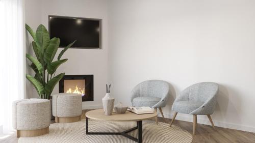 two chairs and a coffee table in a living room with a fireplace at Vieira Residence in Praia da Vieira