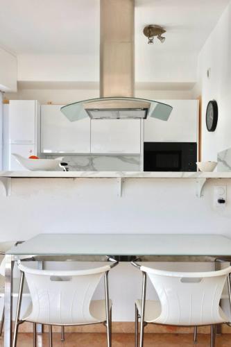 une cuisine avec une table en verre et des placards blancs dans l'établissement 3 Pièces CENTRE DE CANNES, à Cannes