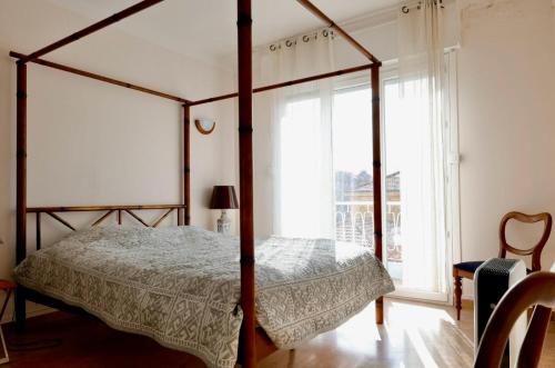 - une chambre avec un lit à baldaquin et une fenêtre dans l'établissement 3 Pièces CENTRE DE CANNES, à Cannes