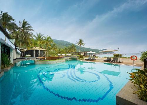 a large swimming pool in a resort with palm trees at The Taaras Beach & Spa Resort in Redang Island