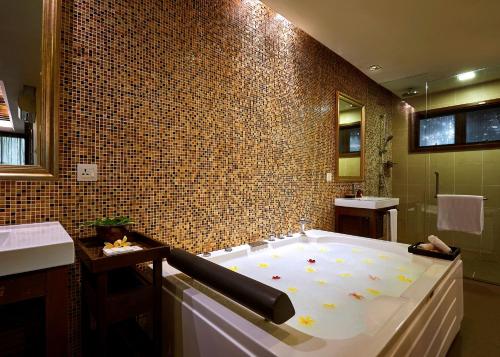 a bathroom with a large tub with a tile wall at The Taaras Beach & Spa Resort in Redang Island