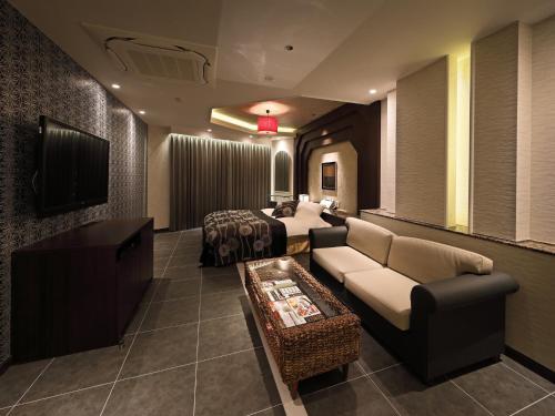 a living room with a couch and a tv at Hotel Le Club PLUS 1 福岡新宮 -Adult Only- in Shingū