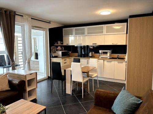 a kitchen with white cabinets and a table and chairs at Le Moderne I Spacieux - 6 p - Hyper Centre in Annemasse