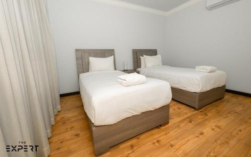 2 camas en una habitación con suelo de madera en Elegant 2-Bedroom Near Airport, en El Cairo