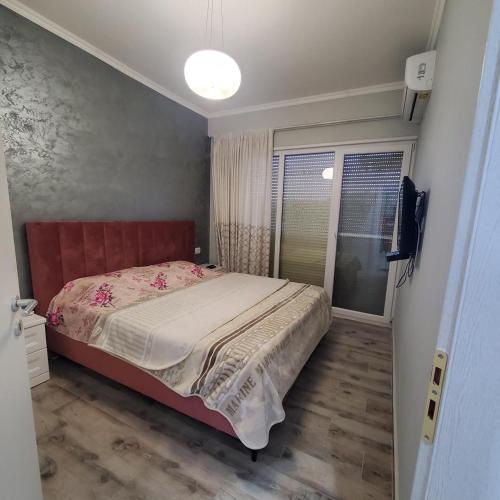 a bedroom with a bed with a red headboard and a window at Urban Charm Lalzi in Draç