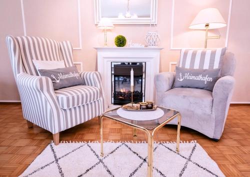 two chairs and a coffee table in a living room with a fireplace at Haus Sonneneck 1 in Bad Zwischenahn