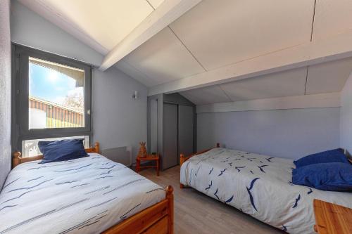 a bedroom with two beds and a window at Villa 13 - En duplex jardin privé à 400m du lac in Biscarrosse