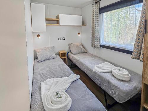 une petite chambre avec deux lits et une fenêtre dans l'établissement Escapade en famille au domaine de litteau, à Litteau