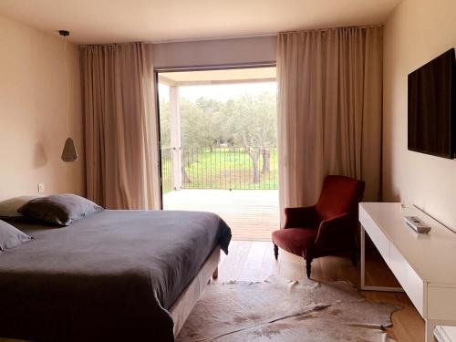 une chambre avec un lit, une chaise et une fenêtre dans l'établissement Villa de Standing avec vue montagne, proche de Porto-Vecchio, à Porto-Vecchio