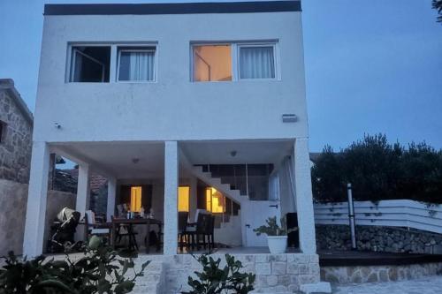 a white house with a table in front of it at Holiday house with a parking space Drvenik , Drvenik - 24088 in Dolići