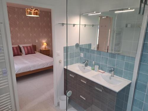 une salle de bain avec un lavabo, un miroir et un lit dans l'établissement Au fil des Champs - Collection Idylliq, à Le Bosc-Roger-en-Roumois