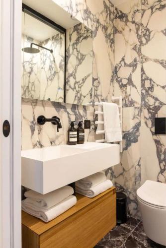 une salle de bain avec un lavabo et un miroir dans l'établissement Chic Apartment with AC 3BR 6P Palais Garnier, à Paris