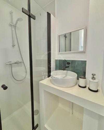 een witte badkamer met een wastafel en een douche bij Maison "Louisette" in Le Touquet-Paris-Plage