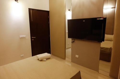 a hotel room with a flat screen tv and a bed at The Luxe Life 2BHK at Supernova in Noida