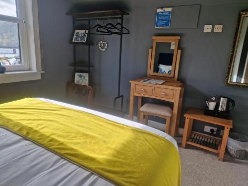 a bedroom with a yellow bed and a mirror at The Dornie in Dornie