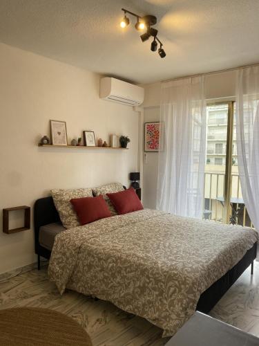 une chambre avec un lit avec des oreillers rouges et une fenêtre dans l'établissement A deux pas des plages et au coeur du vieil Antibes , beau studio rénové, à Antibes