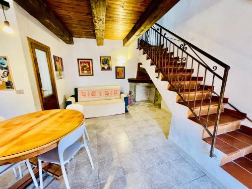 a living room with a wooden table and stairs at Nel Cortile della Casa di Carta, due Singole Unità in Torpè