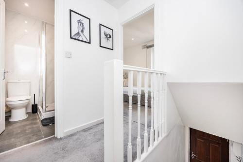 a white bathroom with a toilet and a staircase at Stylish 2BR Home Near Canary Wharf with Garden & Free Parking in London