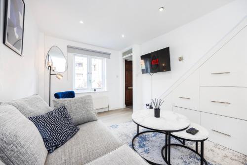 a living room with a couch and a table at Stylish 2BR Home Near Canary Wharf with Garden & Free Parking in London