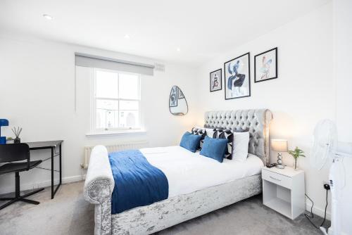 a white bedroom with a bed and a desk at Stylish 2BR Home Near Canary Wharf with Garden & Free Parking in London