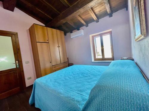 a bedroom with a blue bed and a window at Nel Cortile della Casa di Carta, due Singole Unità in Torpè