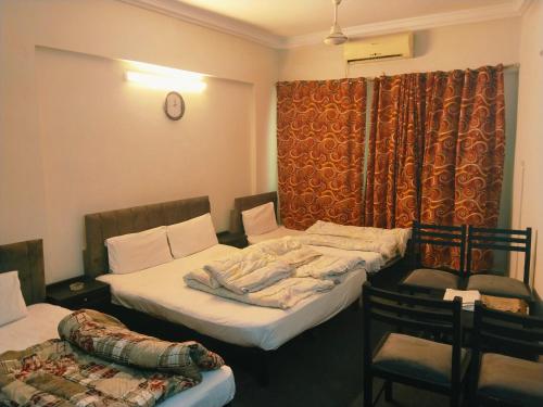 a room with two beds and a chair in it at Grand Arham Hotel in Dargai