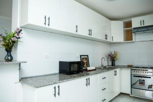 a kitchen with white cabinets and a microwave at Nyamirambo, 2 beds, 2 baths in Kigali