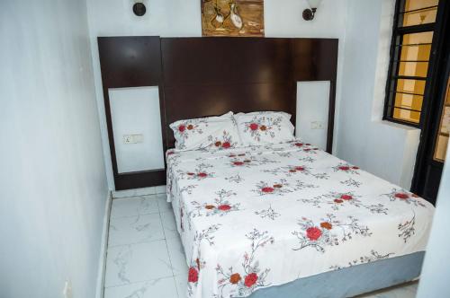 a bed with a white comforter with red flowers on it at Nyamirambo, 2 beds, 2 baths in Kigali