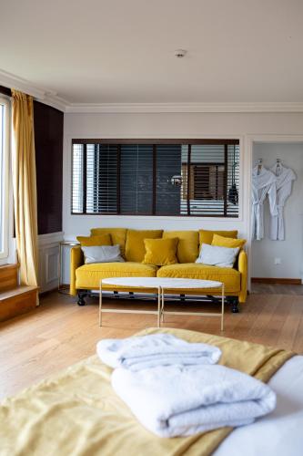 a living room with a yellow couch and a window at Les chambres du Waterzooi in Dunkerque