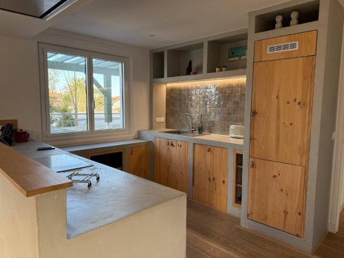 une cuisine avec des armoires en bois, un évier et une fenêtre dans l'établissement Villa Julianna – Élégance et sérénité à Anglet, à Anglet