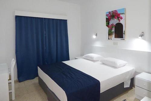 a bedroom with a large bed with a blue curtain at Amore Protaras Apartments in Paralimni
