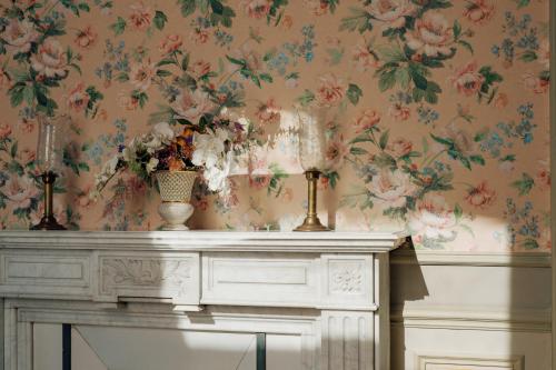 a fireplace with a floral wallpaper on a wall at Villa Pétrusse in Luxembourg