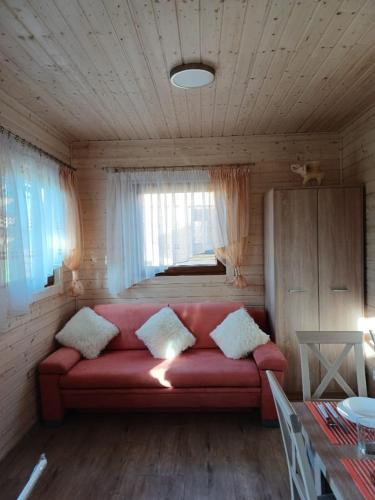 a red couch in a room with a window at Domki Pod Brzozami in Sarbinowo