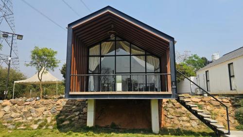 a house with a large window on a stone wall at Aura Farms - Private Pool Cottages in Rāmanagaram