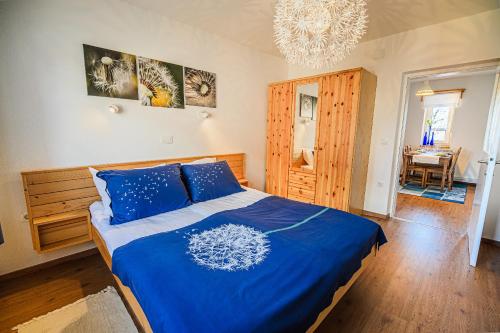 a bedroom with a bed with blue sheets and a chandelier at Apartment House Ančkin kot in Cerknica