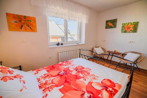 a bedroom with a bed with red flowers on it at Apartment House Ančkin kot in Cerknica