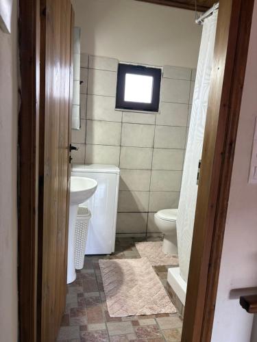 a bathroom with a toilet and a sink and a window at Nikos Traditional House in Maláthiros