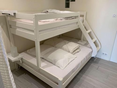 Elle comprend un lit superposé blanc avec des oreillers blancs. dans l'établissement La corvette de la plage Saint Hilaire de RIez, à Saint-Hilaire-de-Riez