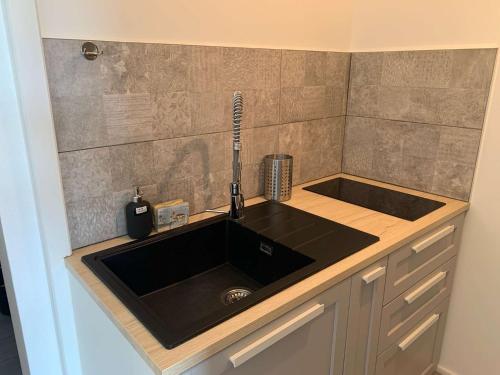 - un comptoir de cuisine avec un évier noir dans l'établissement La corvette de la plage Saint Hilaire de RIez, à Saint-Hilaire-de-Riez