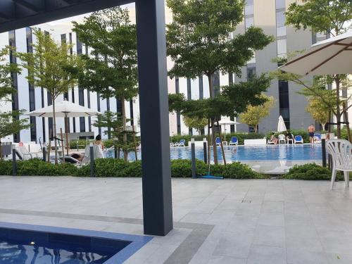 a pool with chairs and an umbrella next to a building at Snazzy Studio, Cozy & Exquisite in Sharjah